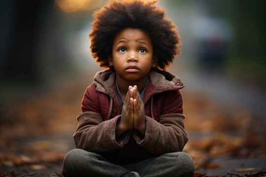 Little poor beggar African American boy praying