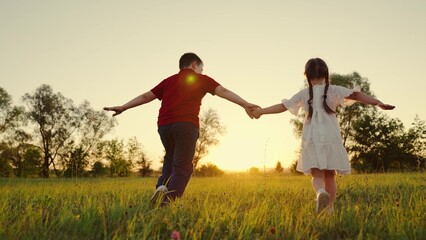 Childrens authentic outdoor experiences. Brother sister run together on green grass. Young children dream fly. Child Boy girl holding hands run across field. Kids play in park. Concept childs dream
