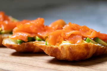 Smoked salmon with cream cheese and avocado slide on fresh croissants.