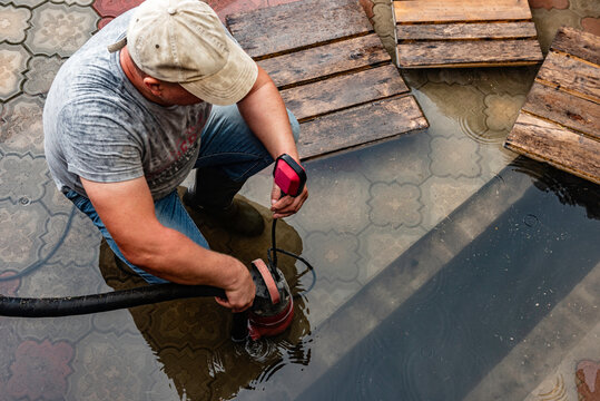 A man pumps out water at the entrance to the garage using a submersible pump.