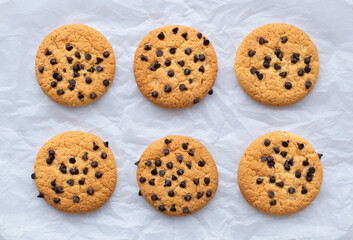 Cookies with chocolate chips on white crumpled paper. Close-up, top view, flat layout