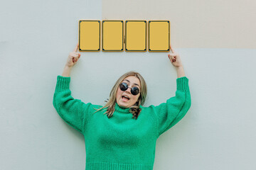 Stylish girl in green sweater holding nameplates on wall