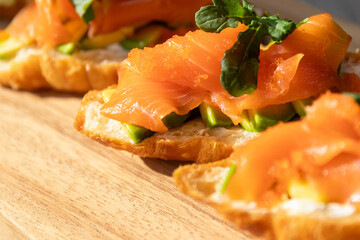 Smoked salmon with cream cheese and avocado slide on fresh croissants.