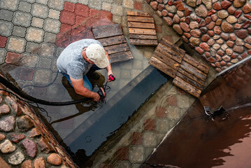 A man pumps out water at the entrance to the garage using a submersible pump.