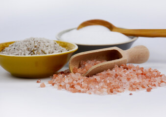 Himalayan pink salt on a white background stock images. Salt and wooden scoop still life stock photo. White, pink and herb table salt stock images