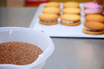 chocolate sprinkles in a bowl with cakes in the background