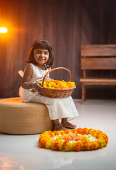 Happy Onam image cute little girl holding flower basket and making Onam Pookalam