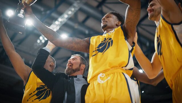 Yellow Team Basketballers Celebrating Successful Victory Over a National Basketball Club, Cheering Together with Teammates and Coaches. Low Angle Cinematic Slow Motion Footage with Happy Athletes
