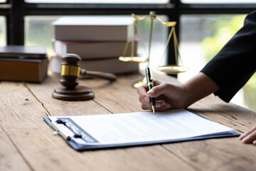 Lawyer working on paperwork in the office. Female lawyer reading contract agreement documents...