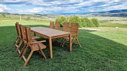Wooden table and chairs, on green meadow, in summer day.