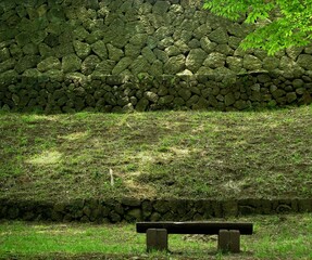 石垣の背景の木陰にベンチのある休憩場所、横位置。