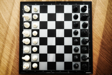 Top view of chess board with figures on the sides. Sunlit wooden table for playing