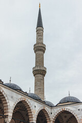 Fototapeta na wymiar very tall mosquee tower standing with dome roofs over cloudy sky