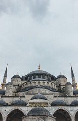 Fototapeta na wymiar very tall mosquee towers standing with huge dome over cloudy sky in vertical symmetry