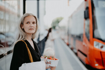 Portrait of a beautiful woman in middle age with gray hair, waiting for the bus at a bus stop.