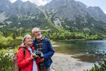 Potrait of active senior woman hiking with husband in autumn mountains.