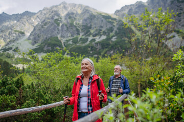 Potrait of active senior woman hiking with husband in autumn mountains.