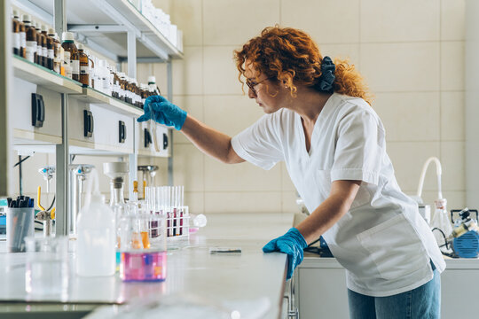 In a bustling chemistry lab, a red-haired female scientist meticulously conducts experiments, igniting her passion for scientific exploration and discovery.