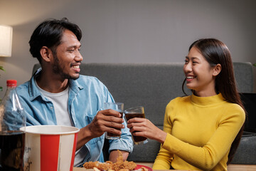 Asian man and woman couple happily eating together inside their home celebrating the weekend.