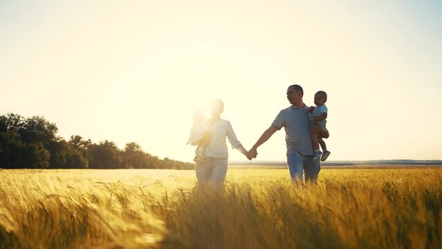 happy family in park wheat field. friendly family walks in a wheat field with two children baby toddlers in summer. happy family kid dream concept. sunlight big family silhouette in wheat field