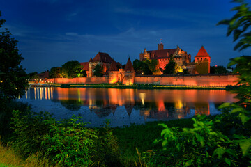Naklejka na ściany i meble The Castle of the Teutonic Order in Malbork by the Nogat river at dusk. Poland