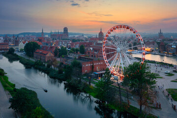 Ferris wheel by the Main Town of Gdansk over the Motlawa river at sunset, Poland.
