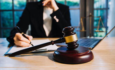 Justice and law concept.Male judge in a courtroom with the gavel, working with, computer and docking keyboard, eyeglasses, on table in morning light