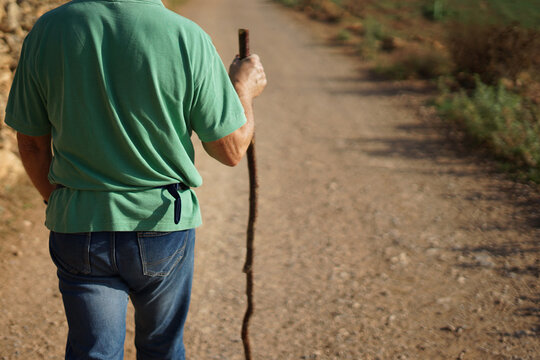 Man walking with a hiking stick on a path. Travel concept