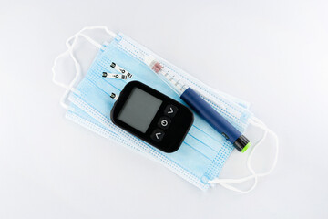 Diabetes day, electronic blood sugar test and insulin pen on fabric mask, top view