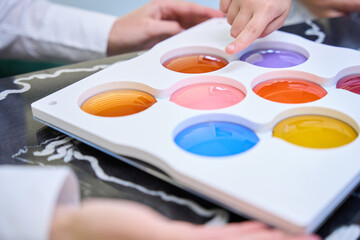 Kid choosing tinted lenses for spectacles in optical shop