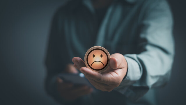 man holding round stick with a sad face icon Expressing extreme dissatisfaction, concept of poor experiences or poor service and customers are not satisfied Low rating in customer feedback evaluation