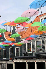 Colorful umbrellas on the street of Volendam city, the Netherlands. Sunny day in Europe. Summer vacation concept. 