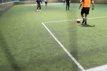 Obraz premium Futsal game with men players on artificial turf field court indoors.