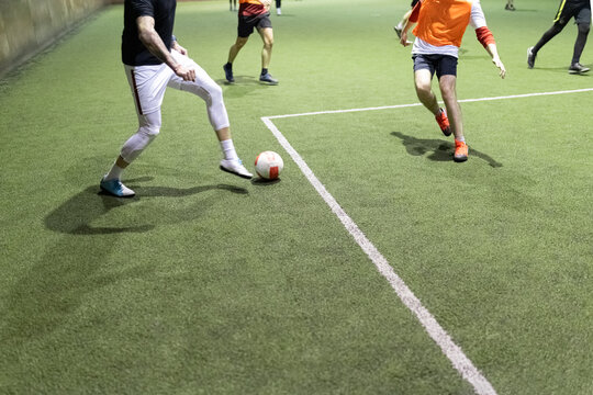 Futsal soccer football player in action on artificial grass court indoors.