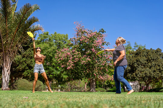 Mom and daughter play matkot in the park on the grass