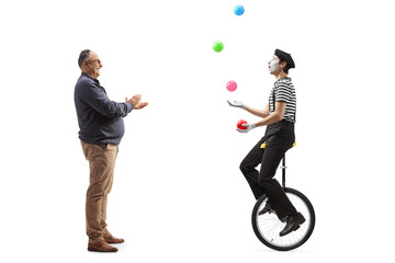 Full length profile shot of a mature man giving an applause to a mime on a unicycle juggling with balls © Ljupco Smokovski