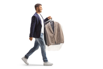 Full length profile shot of a man carrying suit on a hanger with a plastic dry cleaning bag