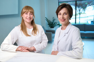 Two women in medical uniforms standing at the reception desk