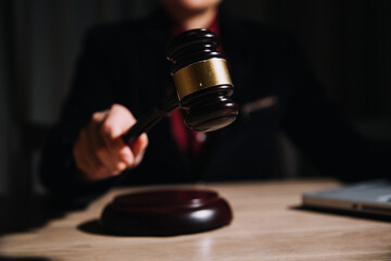Justice and law concept.Male judge in a courtroom with the gavel, working with, computer and docking keyboard, eyeglasses, on table in morning light