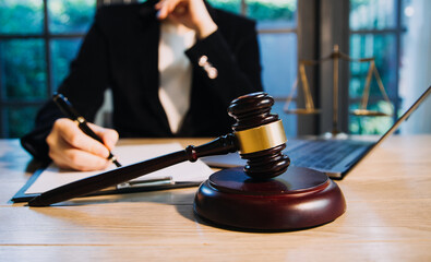 Justice and law concept.Male judge in a courtroom with the gavel, working with, computer and docking keyboard, eyeglasses, on table in morning light