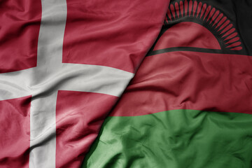 big waving national colorful flag of denmark and national flag of malawi .