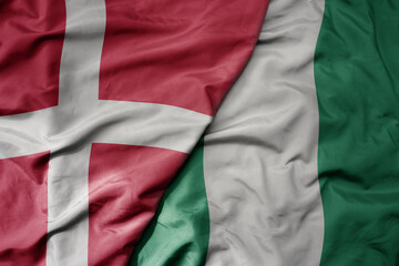 big waving national colorful flag of denmark and national flag of nigeria .