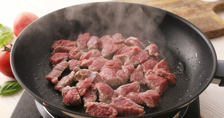 Sliced pieces of raw meat are fried in a frying pan. Roasting beef in a pan. Cooking in the kitchen. Food preparation.