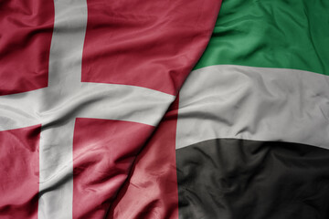 big waving national colorful flag of denmark and national flag of united arab emirates .