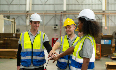 Front view of a diverse group of warehouse workers holding hands to encourage each other in their work.