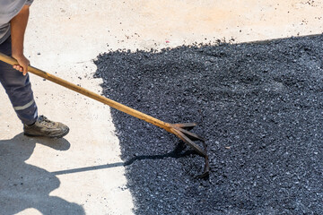 On the sidewalk, road workers leveling freshly laid hot asphalt, aerial view.