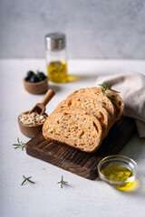 Homemade sourdough ciabatta slice bread with olives and rosemary on a white abstract table. Artisan bread