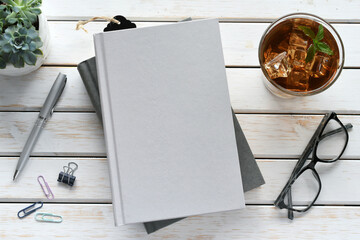Blank book cover for mock up - flat lay with books, drink, plant and reading glasses.