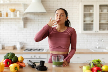 Sporty Fit Lady Tasting Green Detox Smoothie Using Blender Indoors