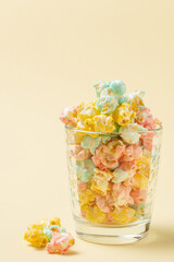 Color glazed popcorn in glass  on yellow background with copy space